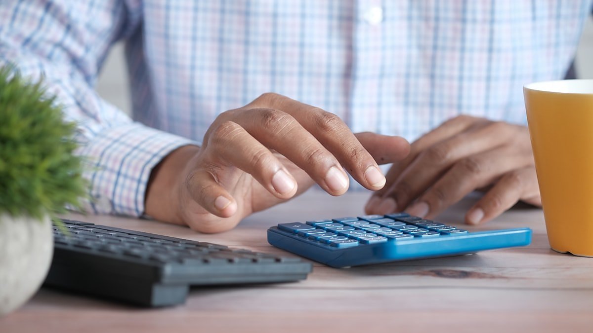 Empresário fazendo contas na calculadora para decidir sobre o regime híbrido