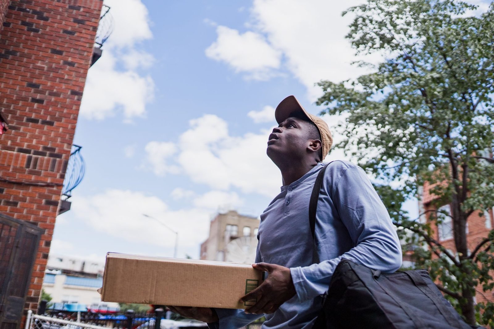 Entregador levando uma encomenda pela rua de um bairro residencial