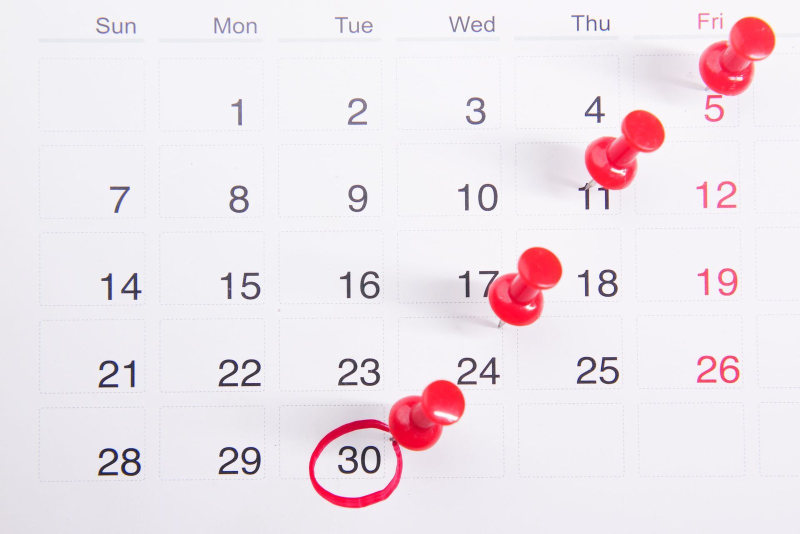 Calendário com alfinetes vermelhos marcando várias datas de vencimento