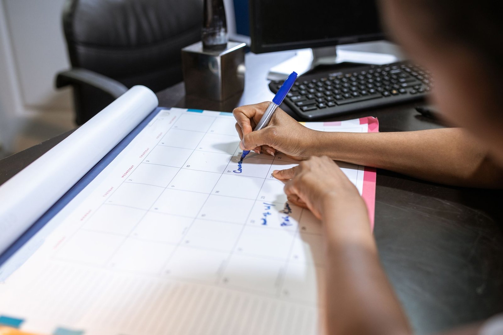 Mulher planejando a agenda em um calendário de mesa no escritório