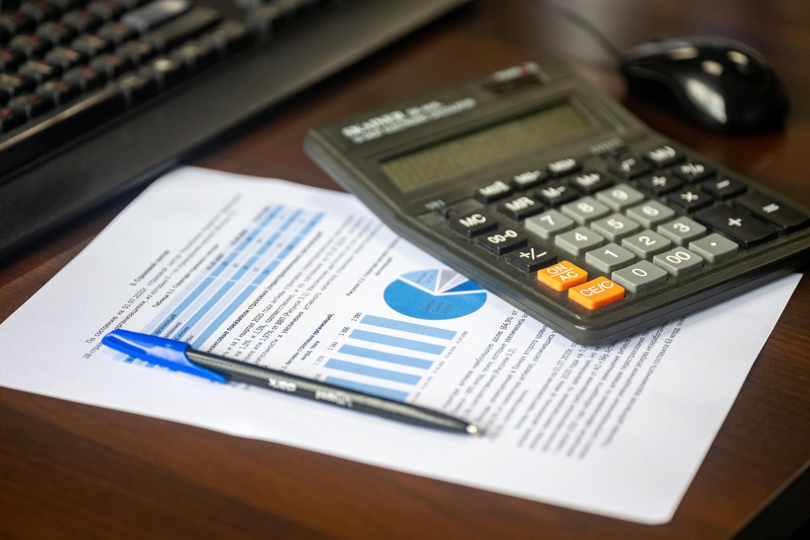 Mesa de trabalho com calculadora, relatório financeiro e caneta