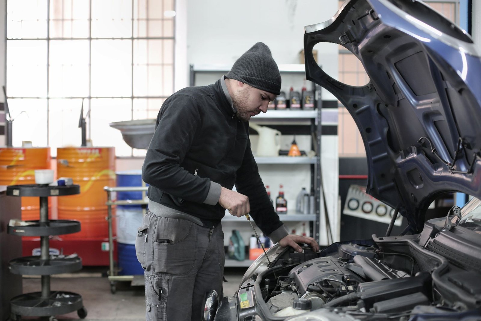 Mecânico inspecionando o motor de um carro com uma lanterna