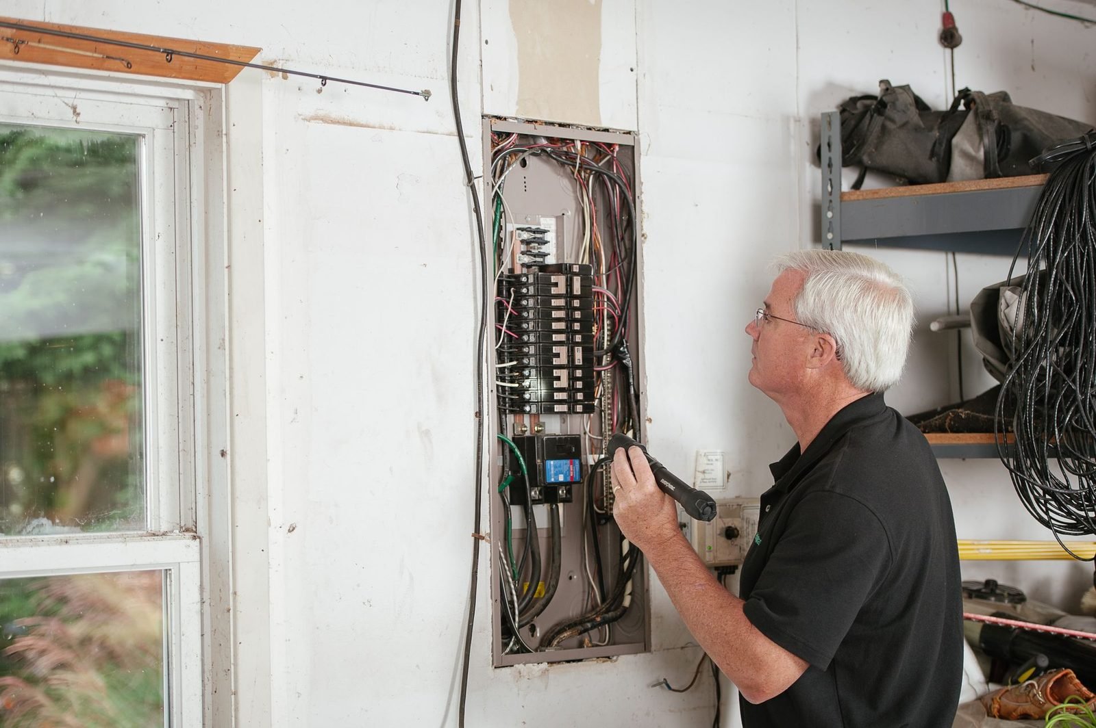 Eletricista examinando o quadro de disjuntores de uma residência