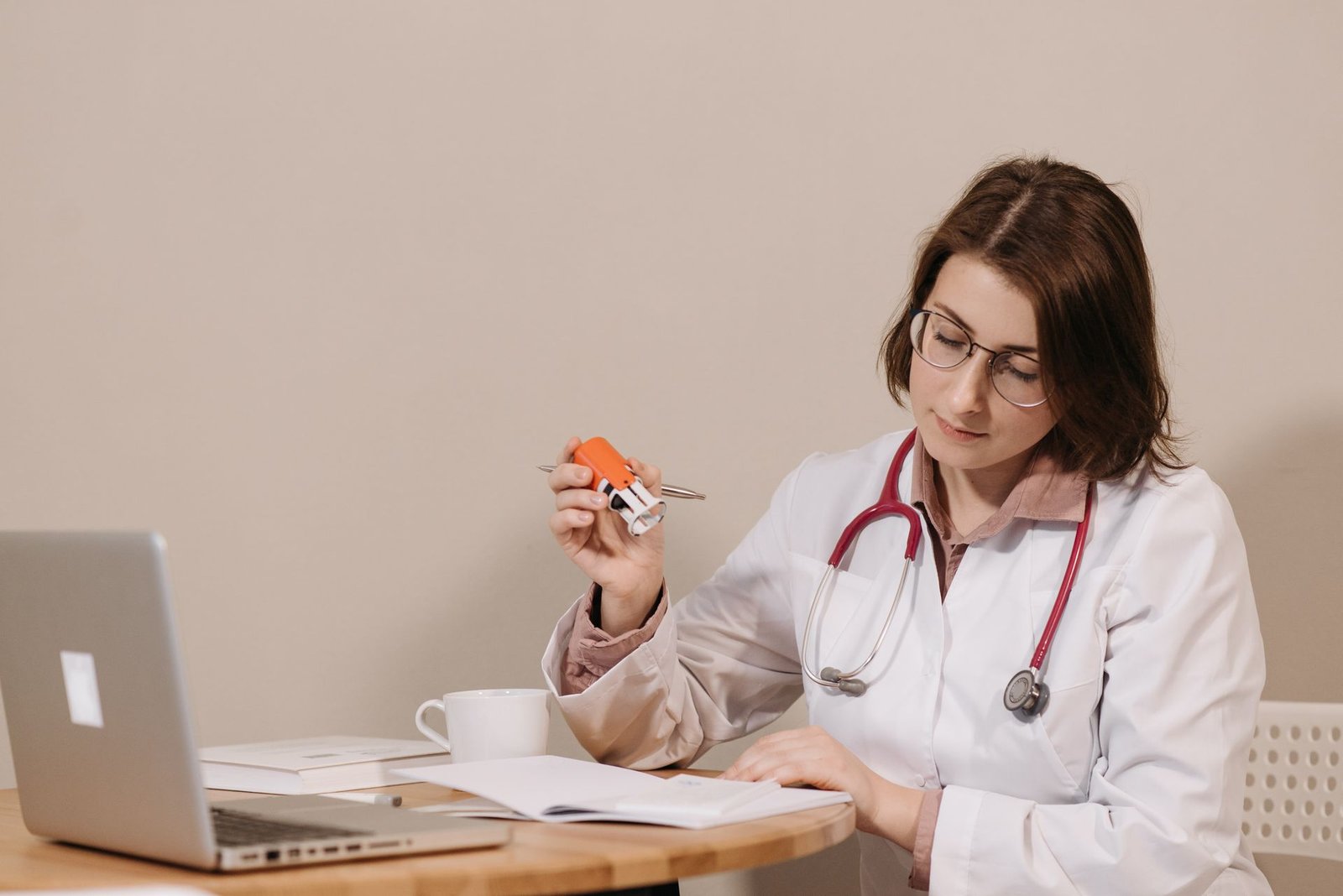 Médica de jaleco branco assinando documentos na mesa do consultório