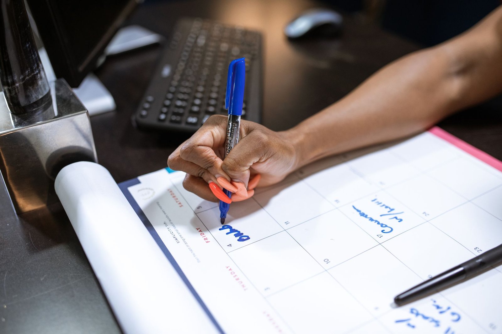 Mão anotando compromissos no calendário de mesa do escritório
