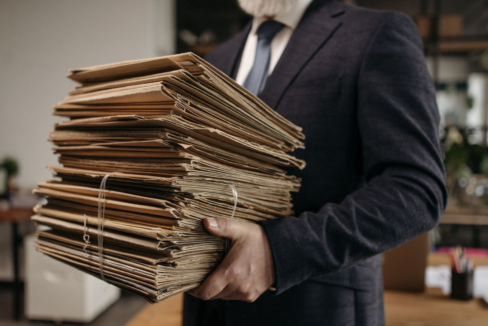 Profissional carregando uma pilha de pastas de documentos no escritório