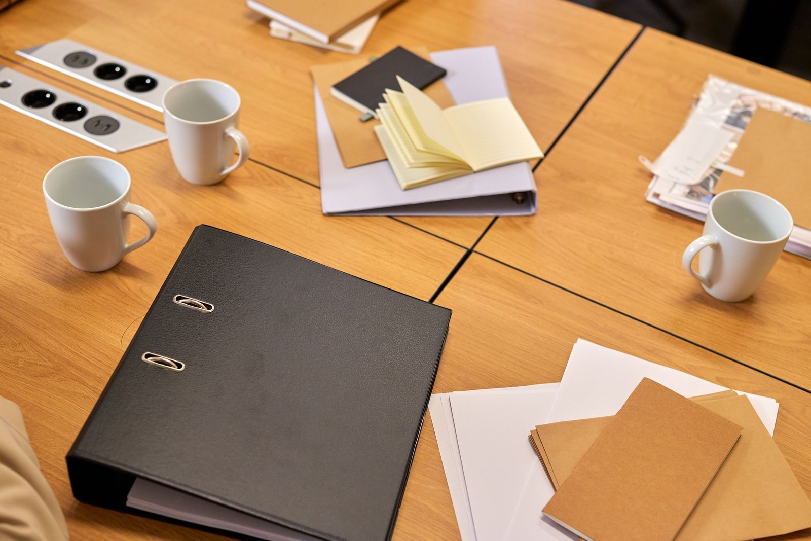 Mesa de escritório com pastas, papéis e canecas organizados para o fechamento