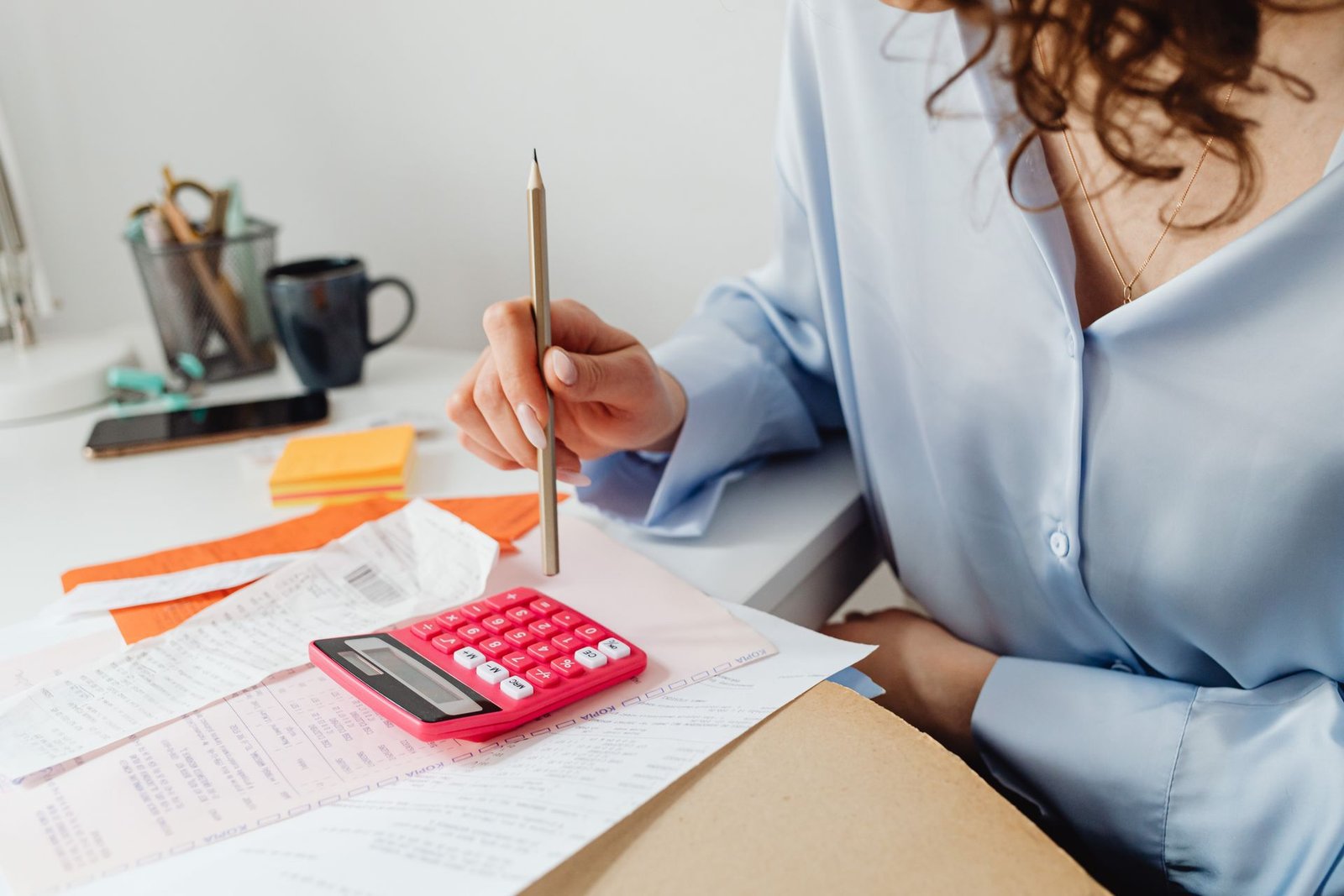 Profissional somando valores na calculadora ao lado de documentos financeiros