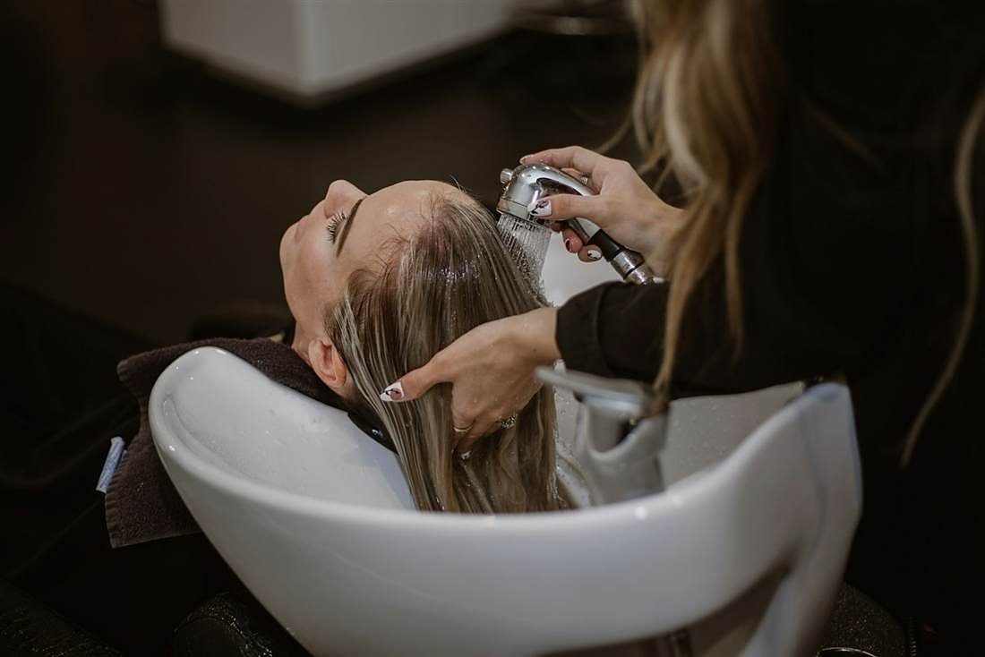 Profissional lavando cabelo de cliente em salão de beleza